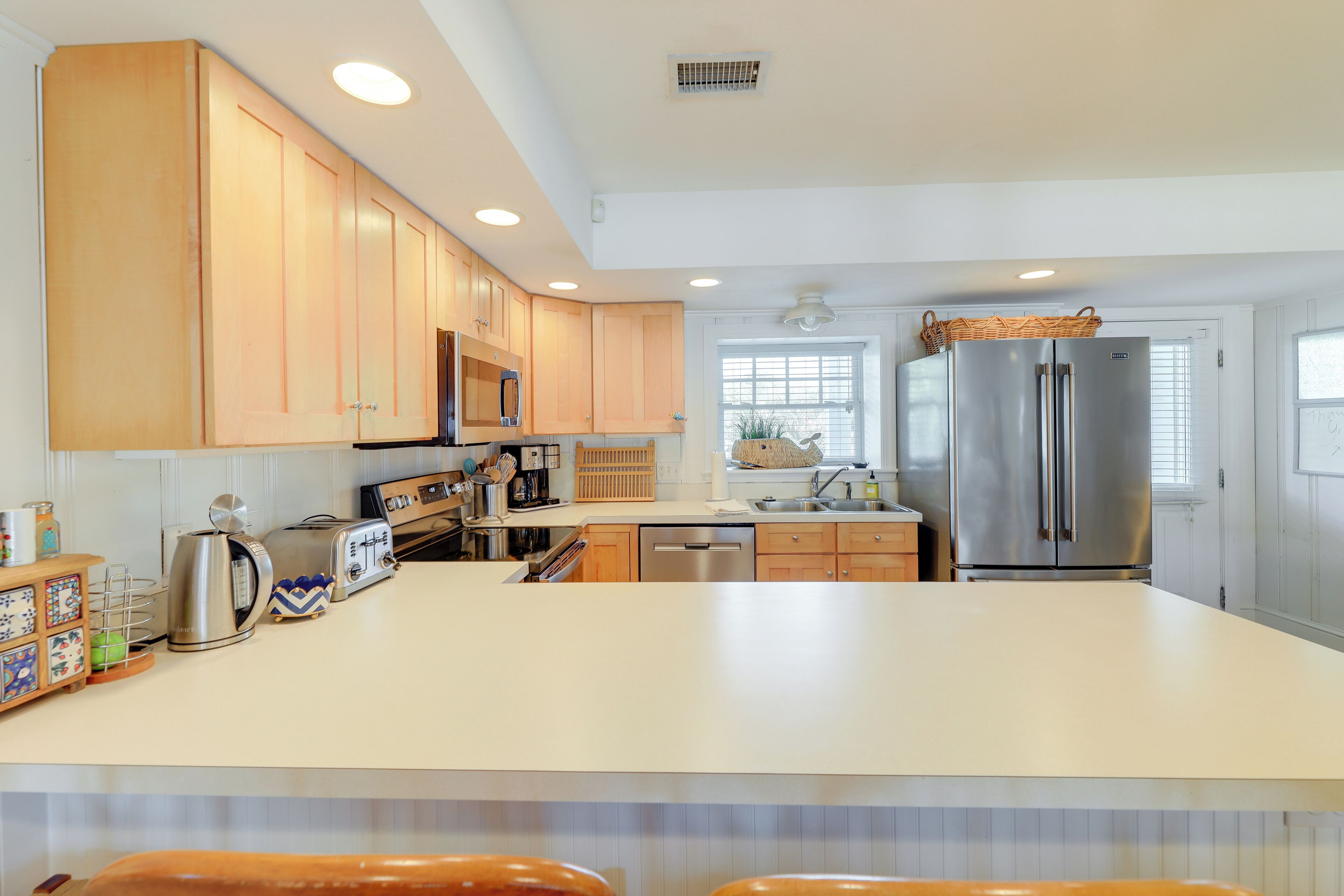 A modern kitchen with wooden cabinets, stainless steel appliances, and a central island.