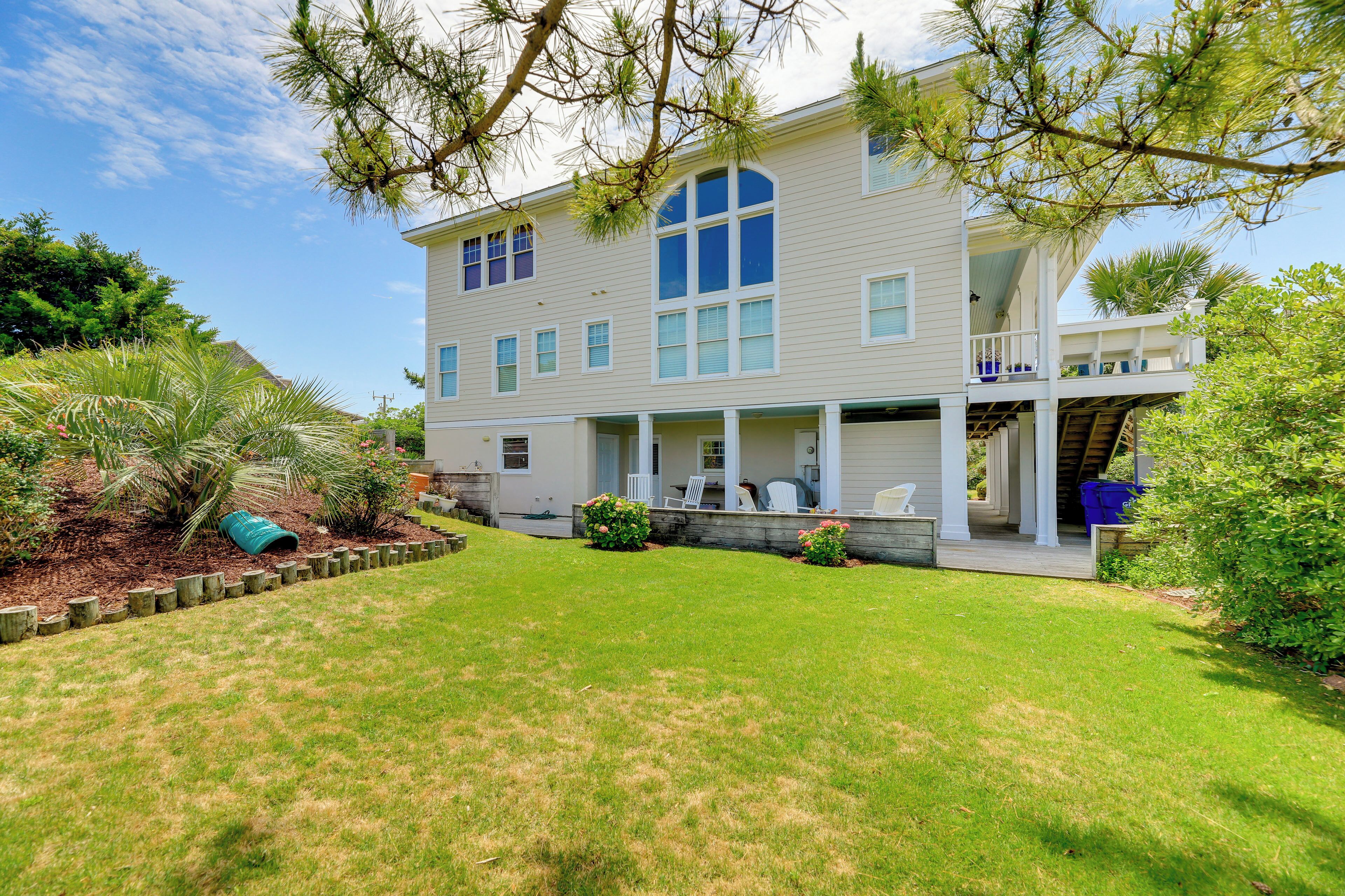 A two-story house with a large front porch, a covered deck, and a well-maintained lawn.