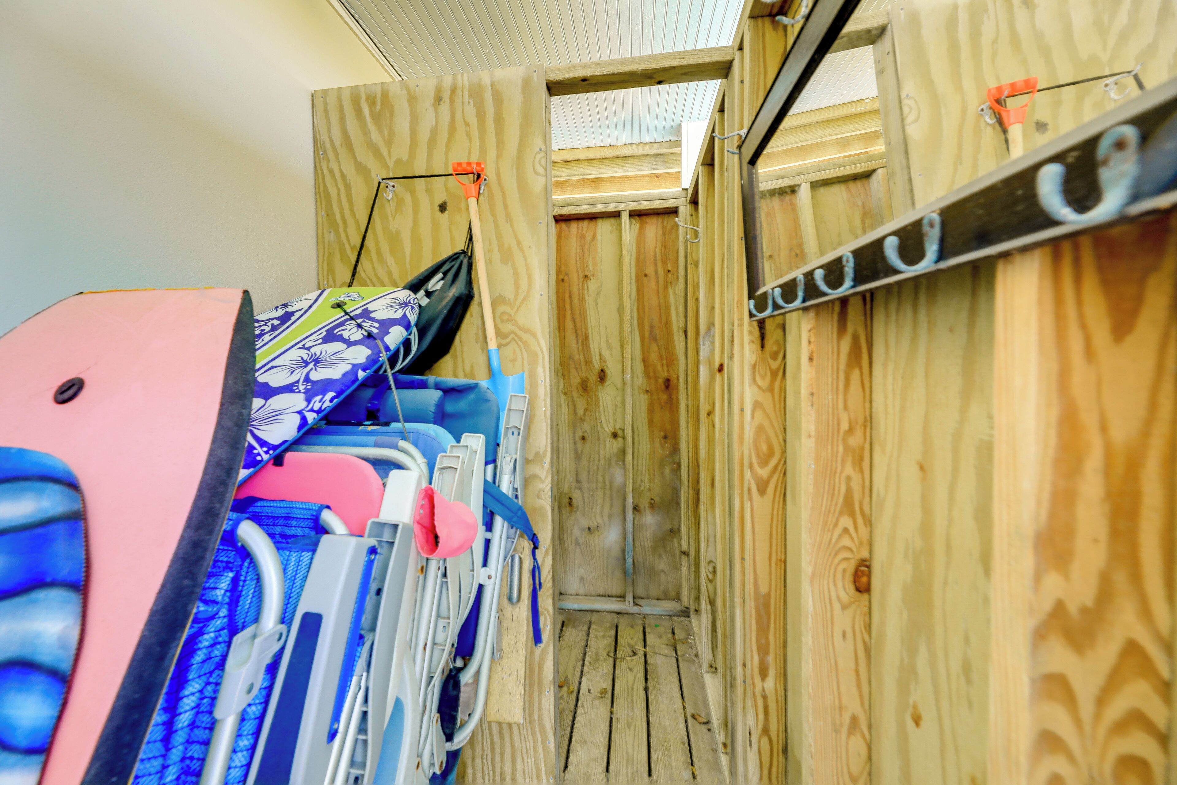 A compact wooden room with bunk beds, a small door, and a metal rack with hooks.