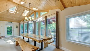 A spacious room with a large wooden table, benches, and a high ceiling with skylights.