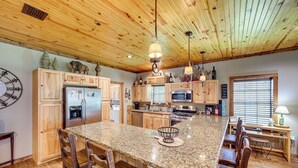 A spacious kitchen with wooden cabinets, granite countertops, and a large island with bar stools. - Jefferson Vacation Rental With Golf Cart! (Jefferson)