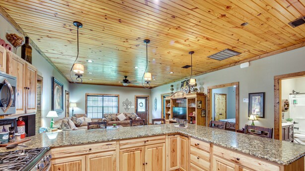 A spacious kitchen with wooden cabinets, granite countertops, a built-in stove, and a large island. - Jefferson Vacation Rental With Golf Cart! (Jefferson)