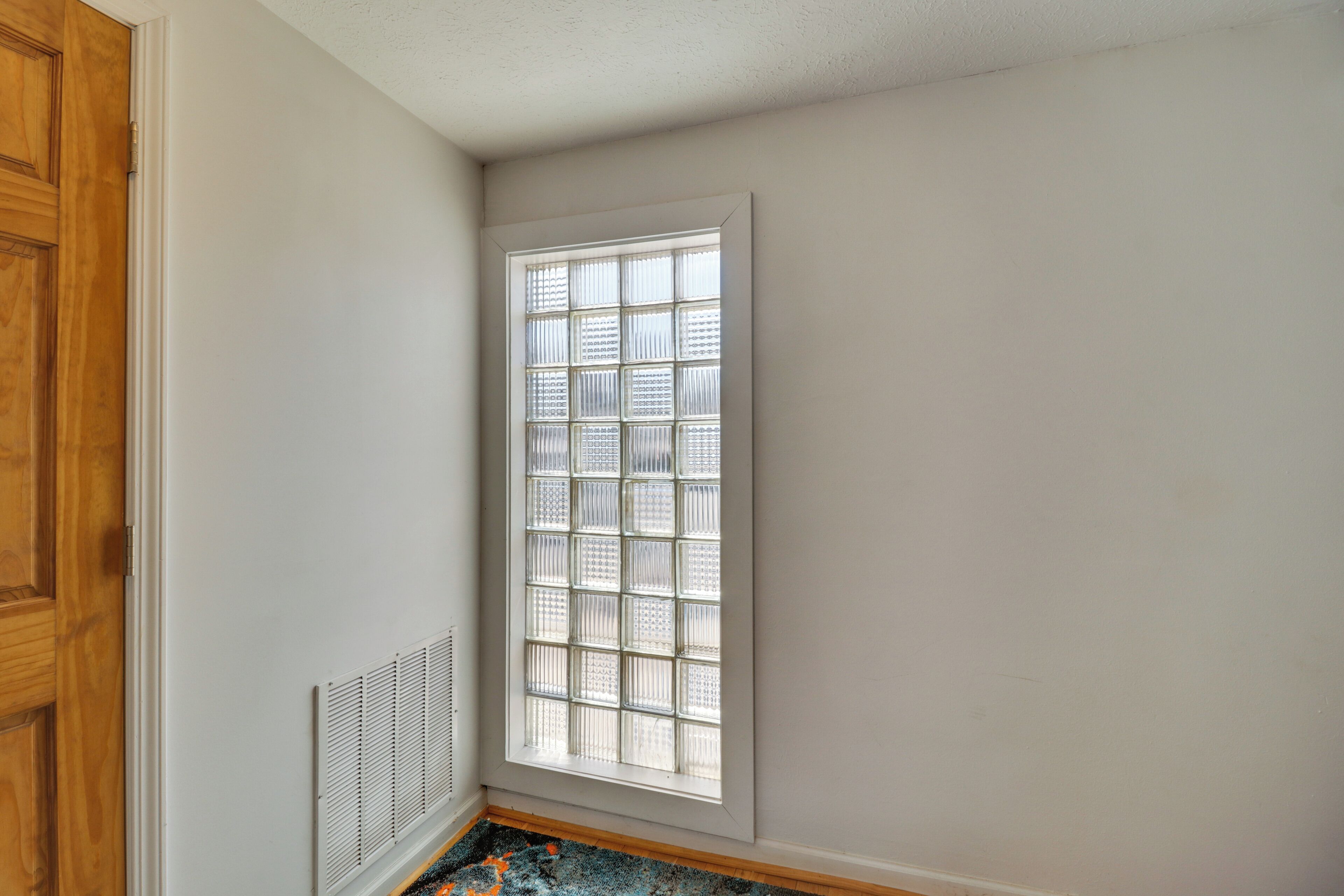 Ein Zimmer mit Ecke, einem großen Fenster, einer Heizung und einer Holztür.