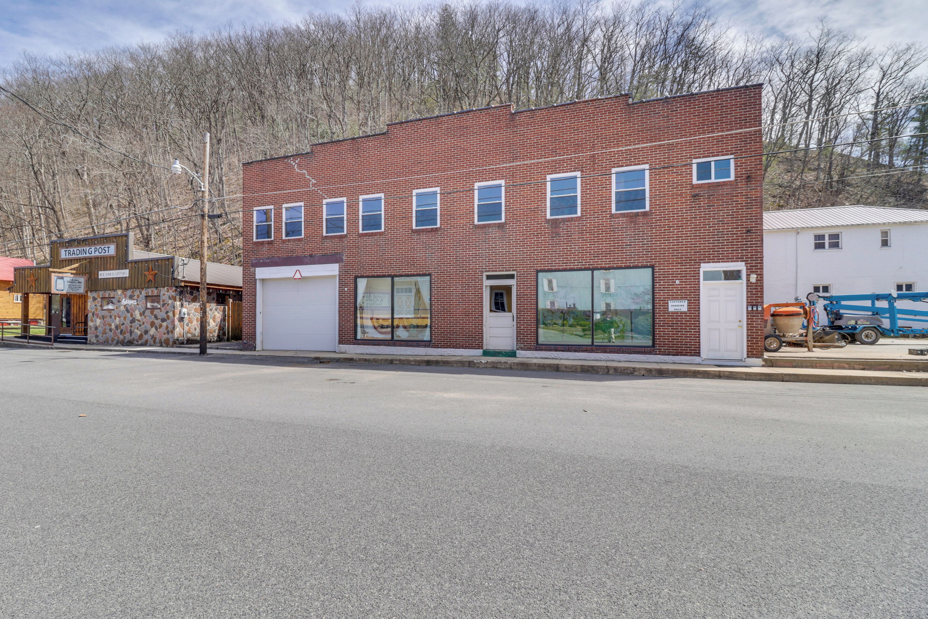 A two-story brick building with a garage door, large windows, and a sign that reads "TRADING POST."