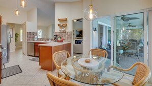A modern kitchen with a glass dining table, wicker chairs, and pendant lighting. - Cheery Fort Myers Vacation Rental w/ Private Pool! (Fort Myers)