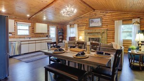 A log cabin interior with a dining area, kitchen, and fireplace. - Cozy Brookville Home w/ Fire Pit & Deck! (Brookville)