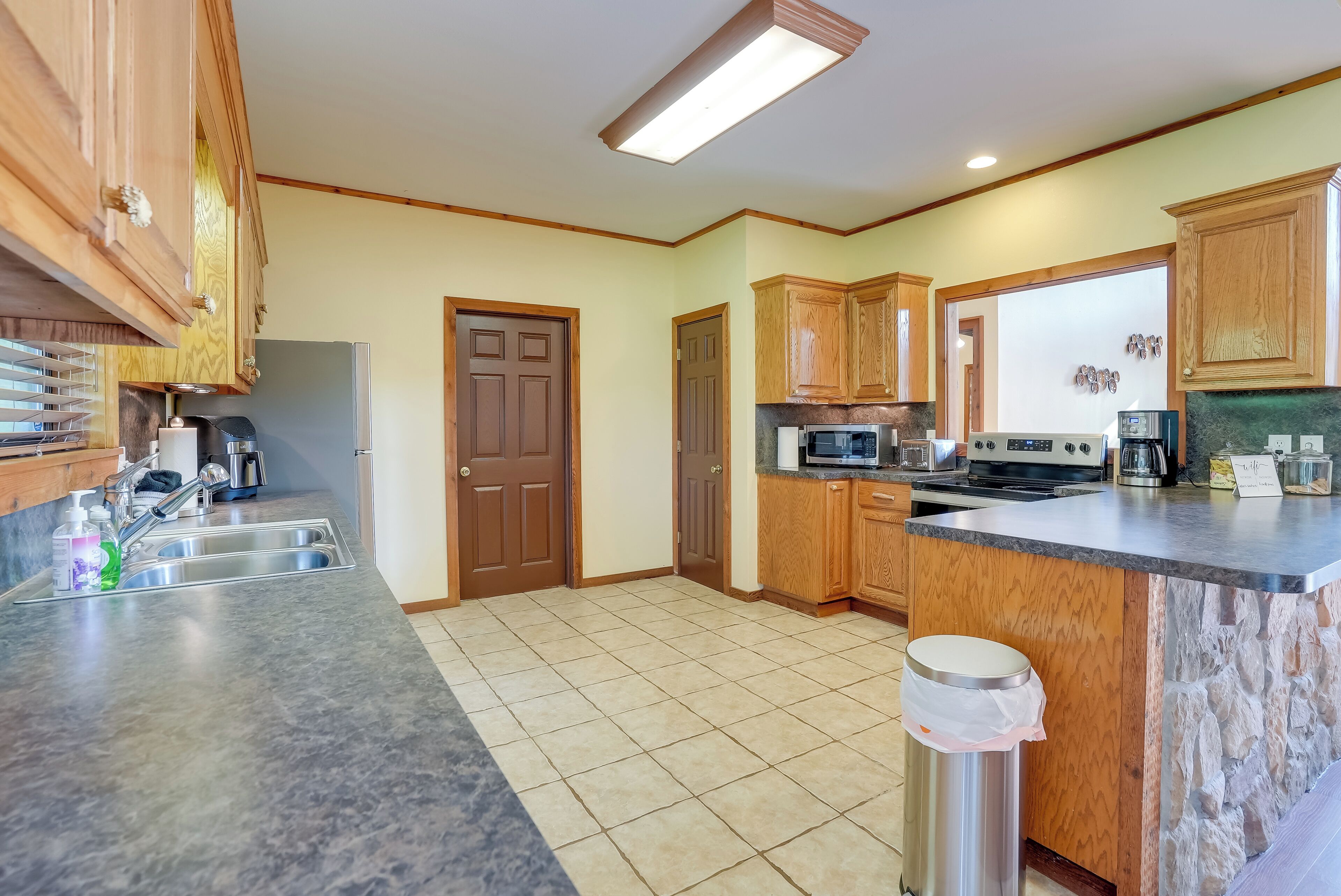 A kitchen with wooden cabinets, a granite countertop, a stainless steel sink, and a built-in oven.
