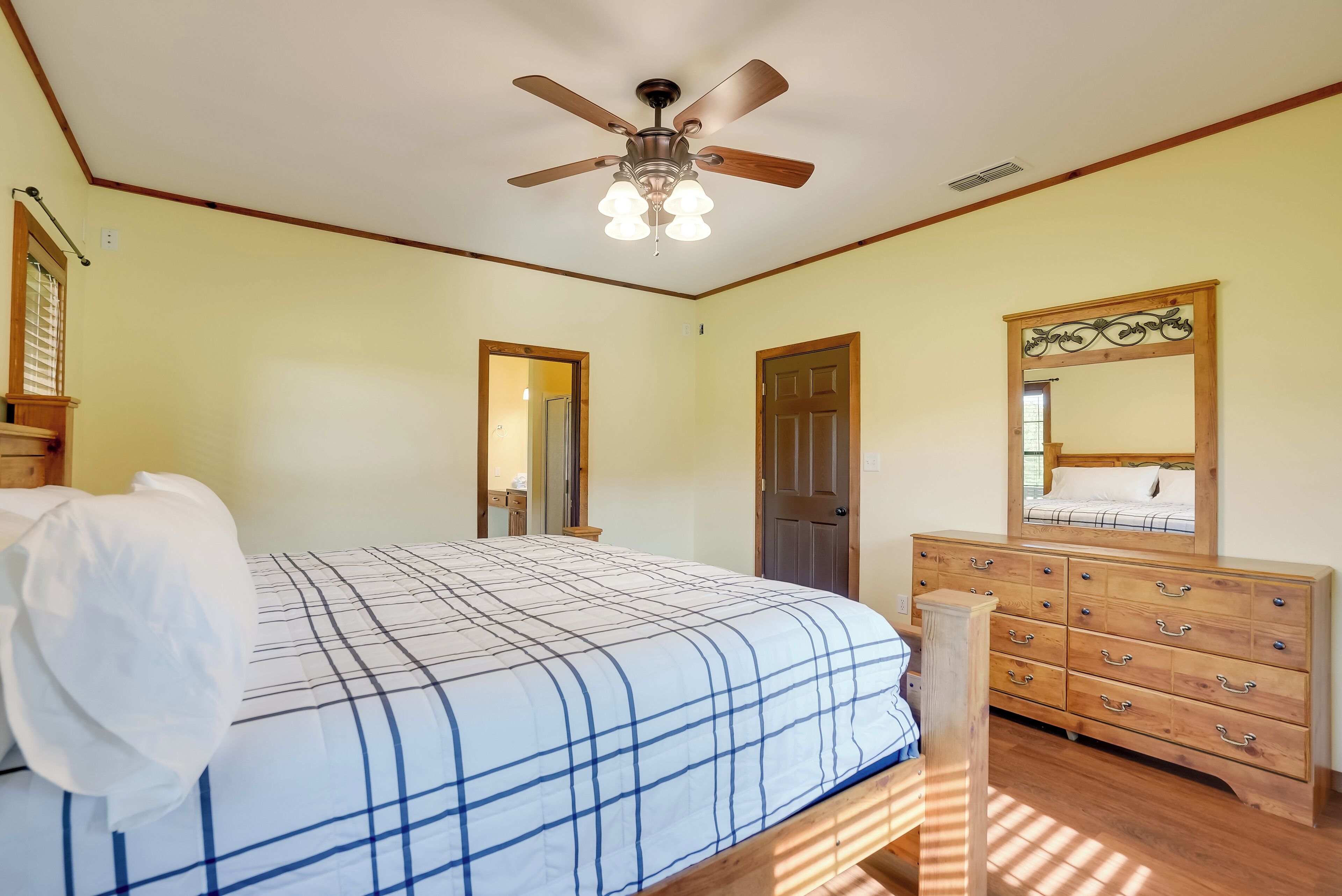 Ein Schlafzimmer mit Bett, Kommode, Deckenventilator und Spiegel.