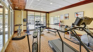 Een fitnessruimte met loopbanden, hometrainers en fitnessapparatuur.