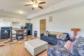A modern living room with a sofa, ottoman, and a dining area with a table and chairs. - Cozy Marlinton Vacation Rental: Downtown Location! (Marlinton)
