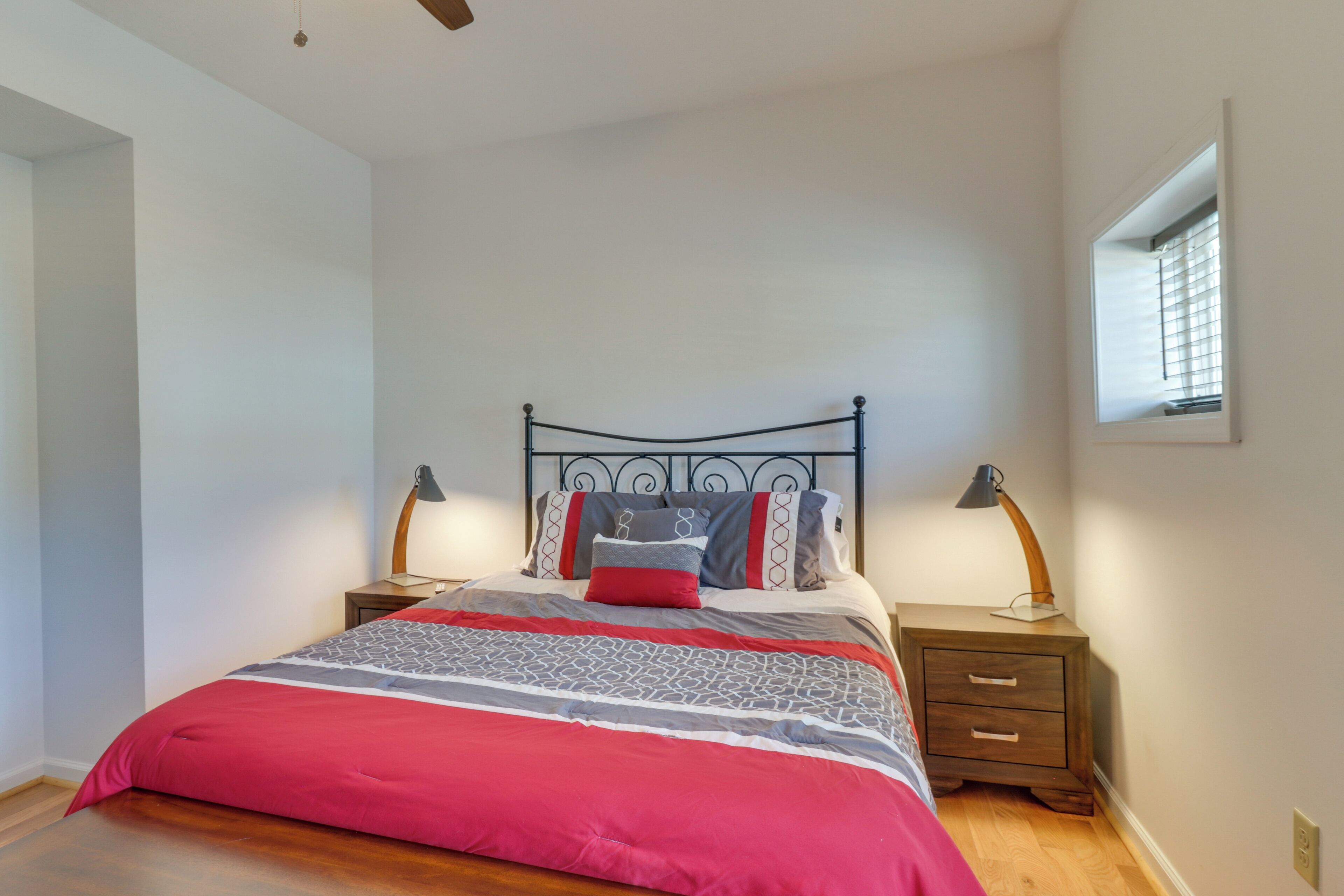 A bedroom with a bed, two bedside tables, a window, and a ceiling fan.