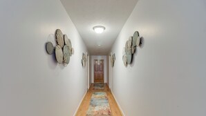 Un pasillo con piso de madera, un tapete colorido y decoración en las paredes.