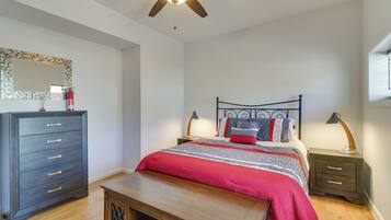 A bedroom with a bed, a dresser, a nightstand, a ceiling fan, and a mirror.