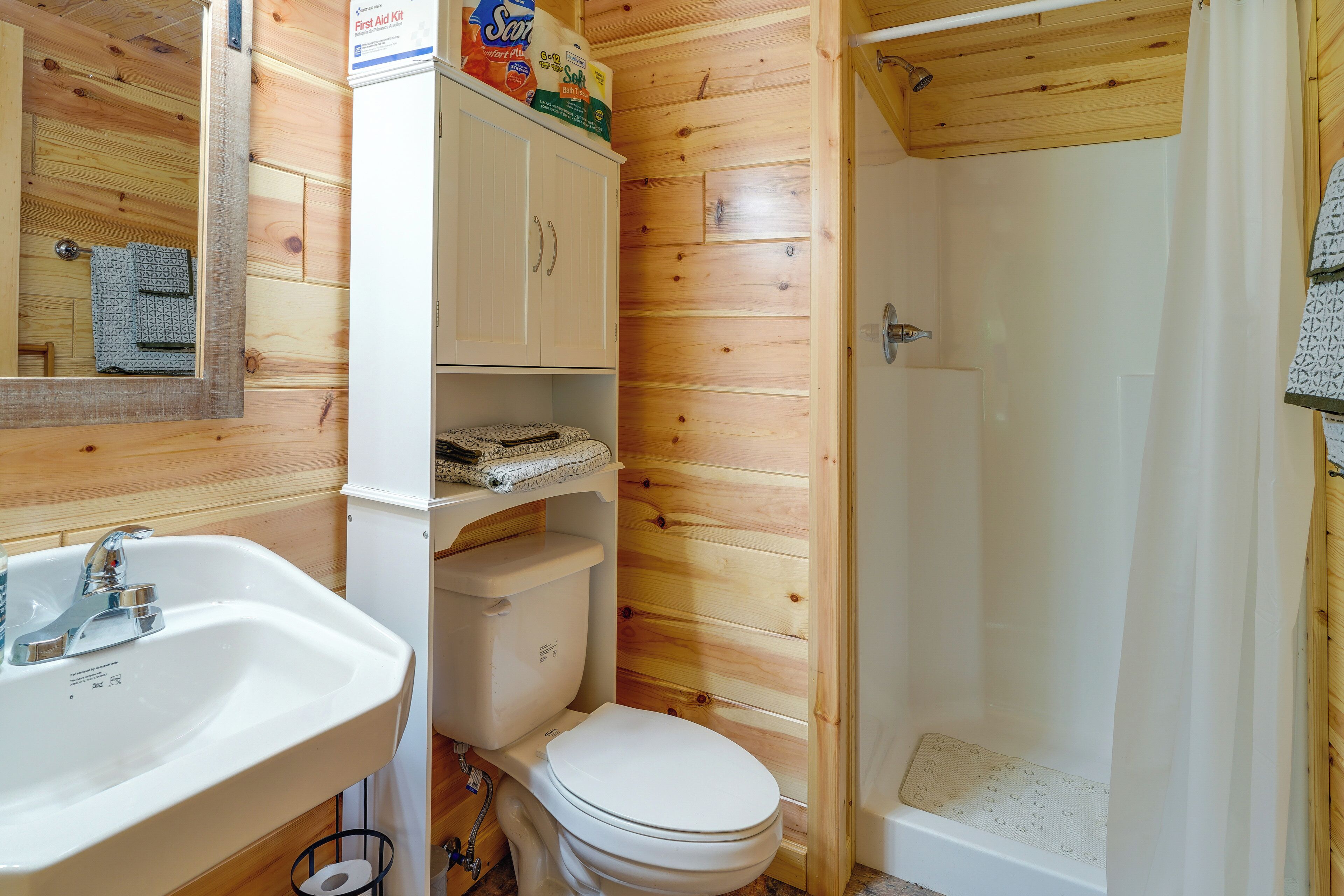 A compact bathroom with a sink, toilet, and shower.