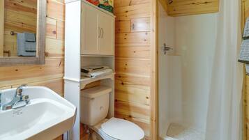 A compact bathroom with a sink, toilet, and shower.