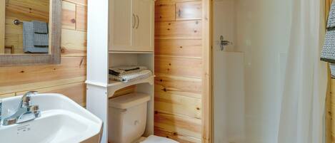 A compact bathroom with a sink, toilet, and shower.