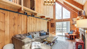 Un interior de madera acogedor con un sofá modular, una mesa de centro y una chimenea.