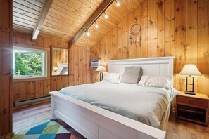 Une chambre à coucher aux murs lambrissés, avec un lit, des lampes de chevet et une fenêtre.