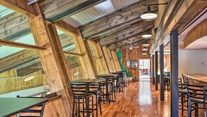 Un restaurante con vigas de madera, techos altos y una barra larga con taburetes.