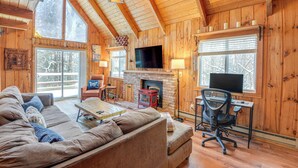 Interior acogedor de una cabaña con un gran techo de madera, una chimenea, un televisor y un espacio de descanso cómodo.