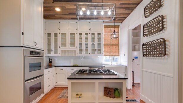 A modern kitchen with white cabinetry, a central island, stainless steel appliances, and decorative wall art. - WFH Friendly: Abode w/ Balcony in Columbus! (Columbus)