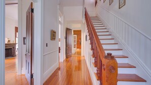 A hallway with wooden flooring, white walls, and a wooden staircase with a handrail. - WFH Friendly: Abode w/ Balcony in Columbus! (Columbus)