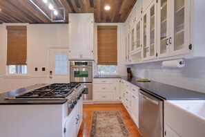 A modern kitchen with white cabinetry, stainless steel appliances, and a wooden floor. - WFH Friendly: Abode w/ Balcony in Columbus! (Columbus)
