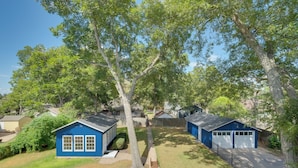A residential area with two blue garage-style buildings, a tree-lined yard, and a clear sky. - WFH Friendly: Abode w/ Balcony in Columbus! (Columbus)