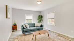 A modern living room with a green sofa, a wooden coffee table, and a large woven rug. - Pet-friendly Connecticut Retreat Near Golfing! (Waterbury)