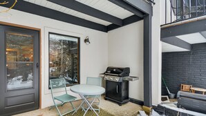 Ett takförsett utomhusområde med en grill, ett bord och stolar.
