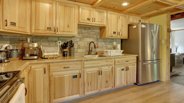 Una cocina con armarios de madera, un refrigerador de acero inoxidable, salpicadero de piedra y encimera de madera.