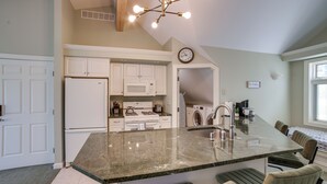 A kitchen with white cabinets, a granite countertop, a built-in microwave, a sink, and a clock on the wall. - Jackson Lakefront Getaway w/ Balcony, Dock Access (Jackson)