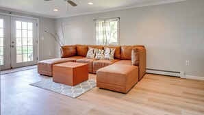 A spacious living room with a brown leather sofa, a matching ottoman, and a ceiling fan. - Lexington Home w/ Sunroom ~ 1 Mi to Lake Huron! (Lexington)