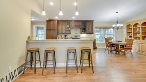 A spacious kitchen with wooden cabinets, a central island with stools, and pendant lighting. - Hawthorne Vacation Rental w/ Access to Cue Lake (Hawthorne)