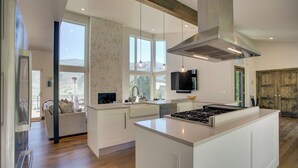 A modern kitchen with a large island, pendant lighting, and a view of the outdoors. - Avon Vacation Rental w/ Hot Tub & Mountain Views! (Avon)