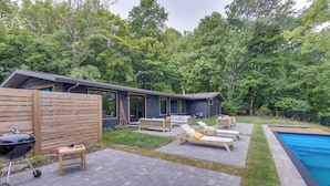 A modern outdoor patio with a pool, lounge chairs, and a barbecue grill. - Riverfront Appleton Home With Pool & Boat Dock! (Appleton)