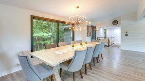 A modern dining room with a wooden table, six grey upholstered chairs, and a unique ceiling light fixture. - Riverfront Appleton Home With Pool & Boat Dock! (Appleton)