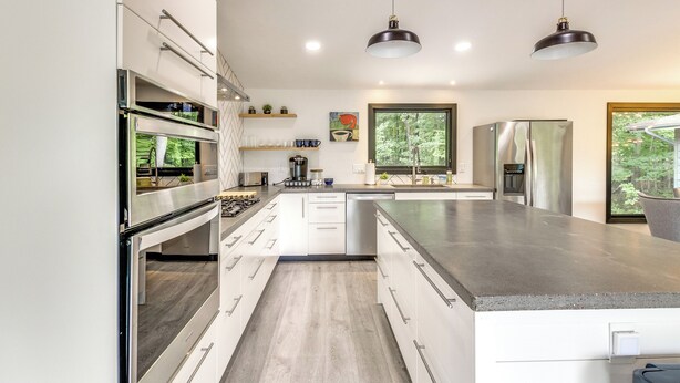 A modern kitchen with stainless steel appliances, white cabinetry, and a large island. - Riverfront Appleton Home With Pool & Boat Dock! (Appleton)