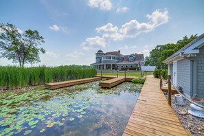 A house with a large deck extending over a pond with lily pads. - Jackson Lakefront Getaway: Boat Dock, Porch, Patio (Jackson)