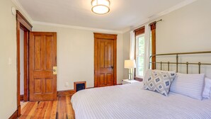 A bedroom with a wooden floor, a bed with a metal headboard, and two wooden doors.