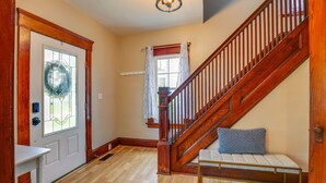A wooden staircase with a bench at the bottom, a door with a glass window, and a light fixture above.