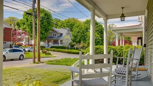 A porch with white rocking chairs and a white picket fence.