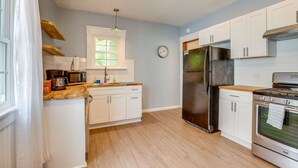 A kitchen with white cabinets, a stainless steel refrigerator, a microwave, and a stove.