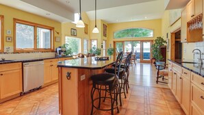 A spacious kitchen with a large island, wooden cabinets, and ample natural light from large windows. - 'lockes Glen' - Lakefront Geneva Getaway w/ Dock! (Geneva)