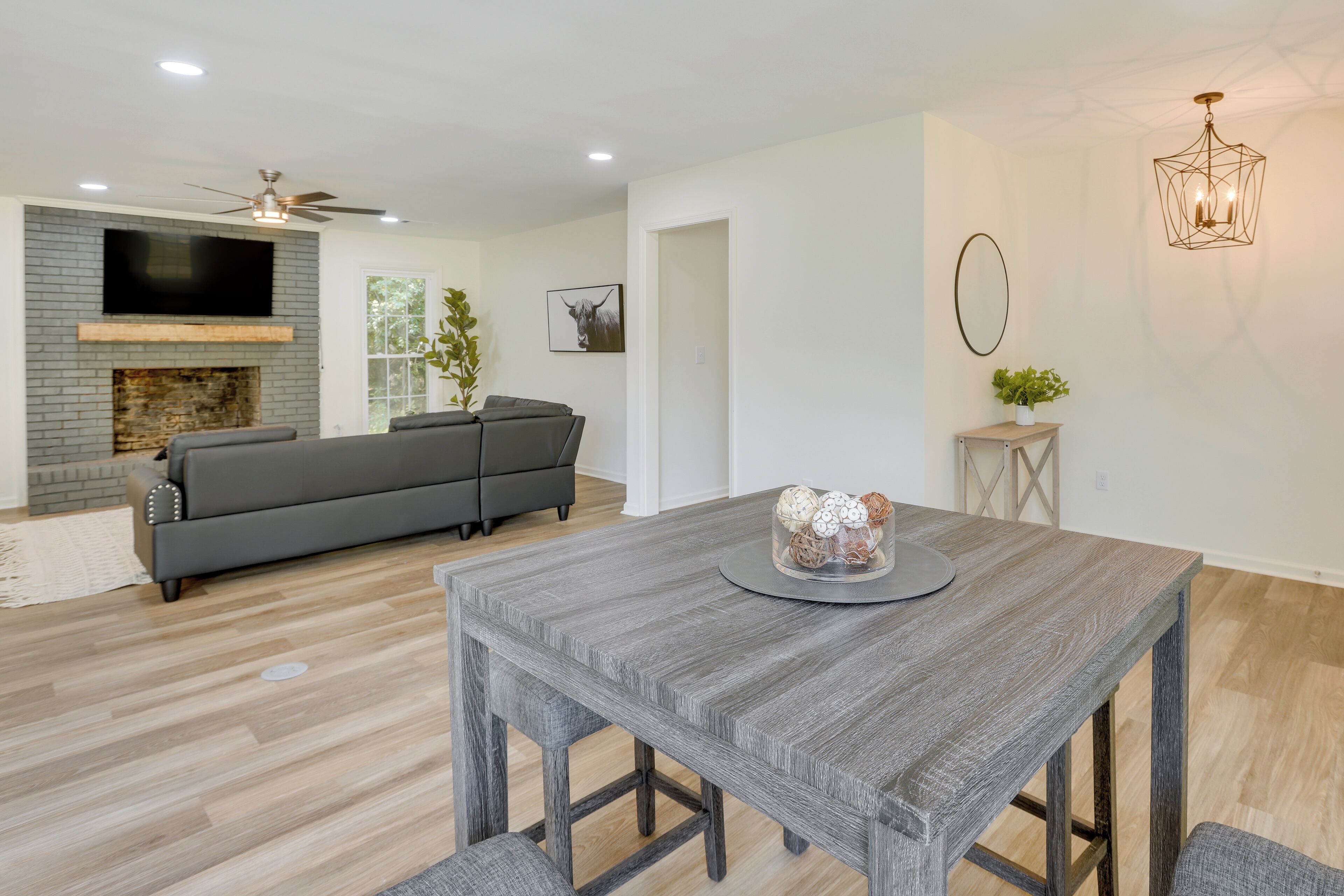 A modern living room with a fireplace, grey sofa, dining table, and decorative items.