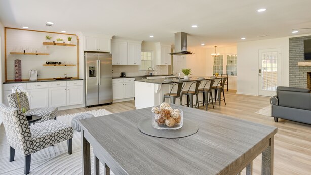 A modern kitchen with white cabinets, a stainless steel refrigerator, and a dining area with a wooden table and chairs. - Northport Game Day Getaway: 5 Mi to University! (Northport)