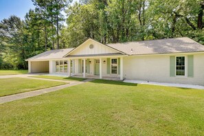 A single-story house with a covered porch, a front lawn, and a wooded backdrop. - Northport Game Day Getaway: 5 Mi to University! (Northport)