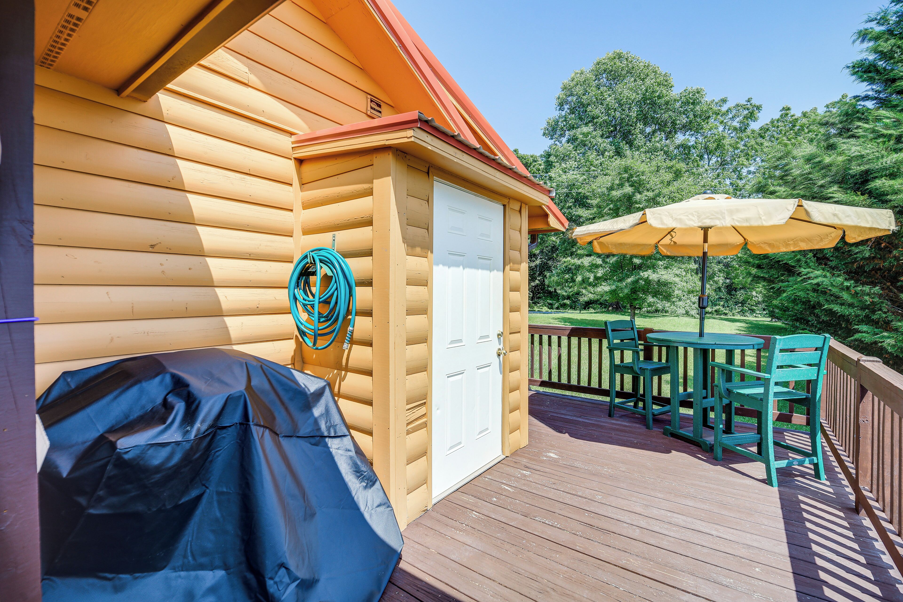 A wooden deck with a covered grill, a white door, and a table with chairs.