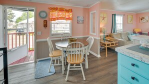 A cozy living room with a dining area, featuring a wooden table and chairs, a blue sofa, and a kitchen area with a blue cabinet. - Walk to Shore: Myrtle Beach House w/ Private Deck! (Murrells Inlet)