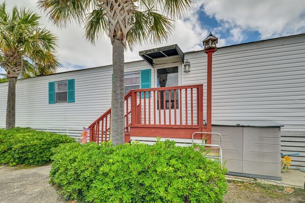 A white mobile home with a red staircase, a small porch, and a garage. - Walk to Shore: Myrtle Beach House w/ Private Deck! (Murrells Inlet)